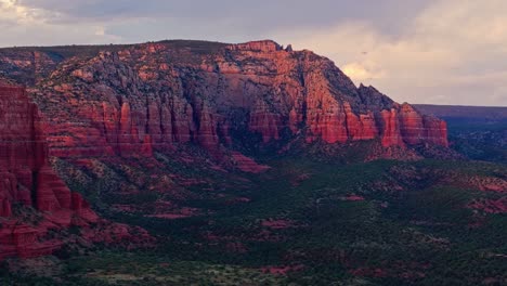 purple red shadows and light spread across sheer sandstone mountains of sedona arizona at dusk, drone