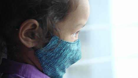 niño mirando por una ventana con una máscara