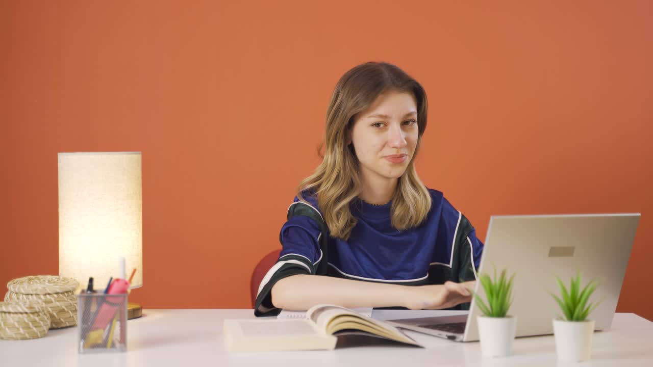 mujer joven mirando la computadora portátil haciendo un gesto positivo.