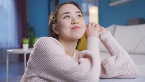 집에서 혼자 앉아서 행복한 순간을 생각하고 미소 짓는 아시아 여성.