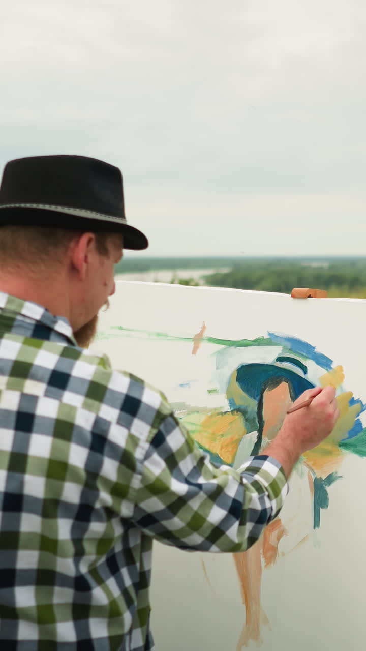 primer plano de un pintor con un sombrero y una camisa a cuadros, centrado en la creación de una obra maestra en un campo cubierto de hierba. en el fondo, una mujer con un sombreiro y un vestido blanco se sienta, posando para la pintura