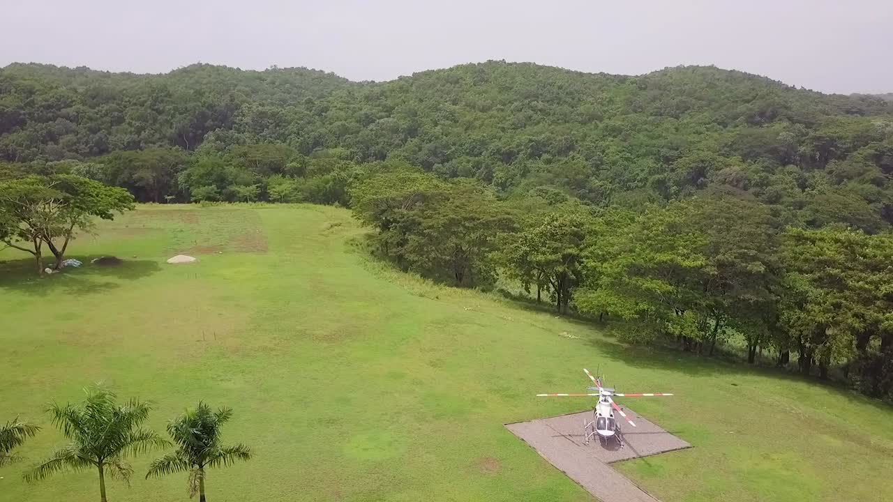 열대 정글 환경의 착륙장에 있는 헬리콥터의 좋은 드론 공중