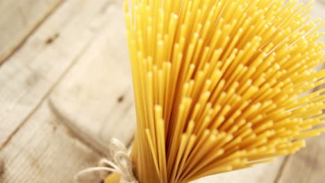 bunch of raw spaghetti tied up vertically with rope on wooden background