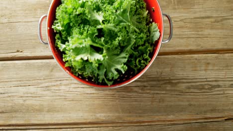 Green-lettuce-leaves-in-cooking-pot-placed-on-wooden-table-4K-4k