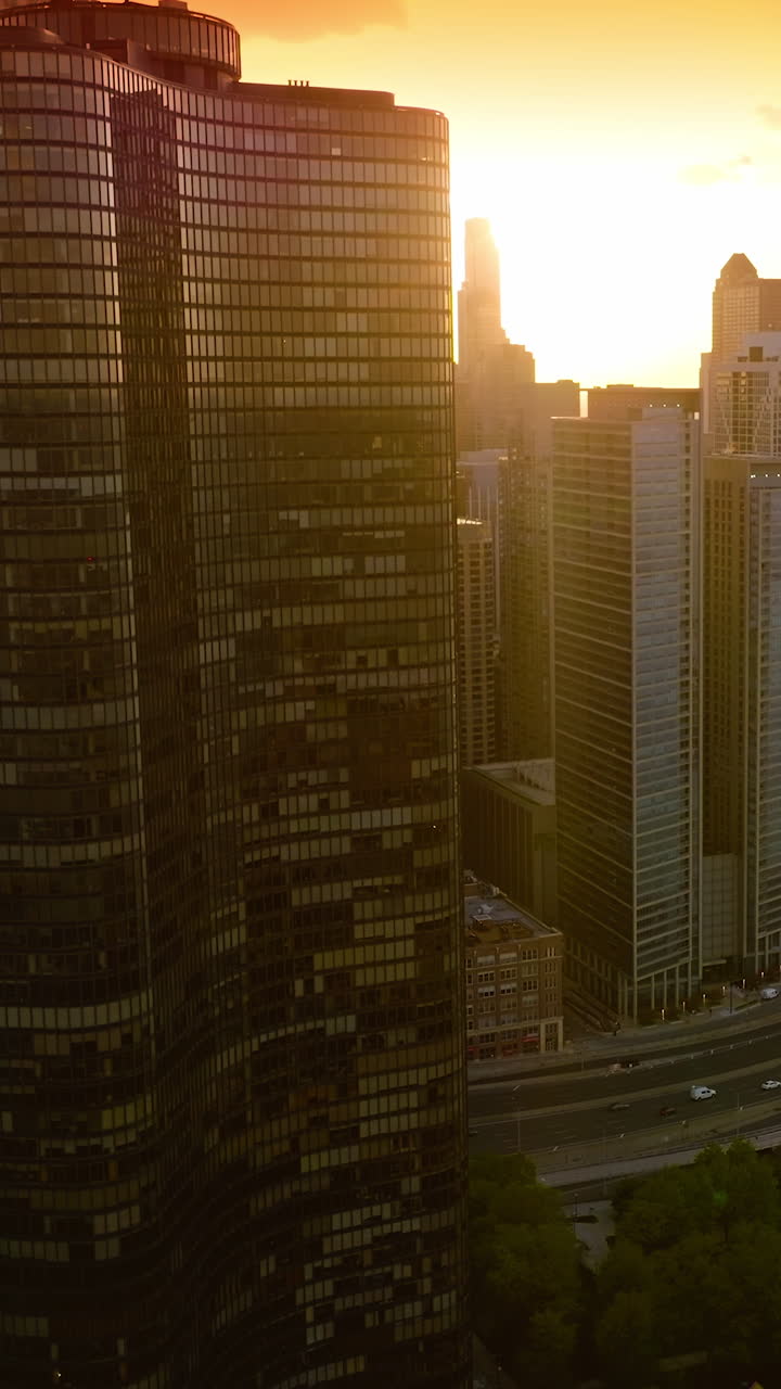 Fantastic skyscrapers standing on the lake waterfront. Amazing city in the rays of setting sun. Vertical video
