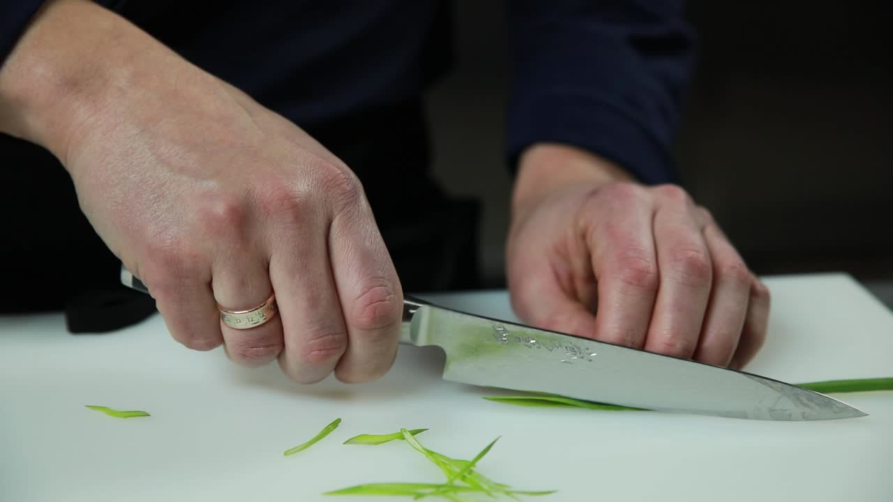 셰프가 초록 양파를 고 있습니다.