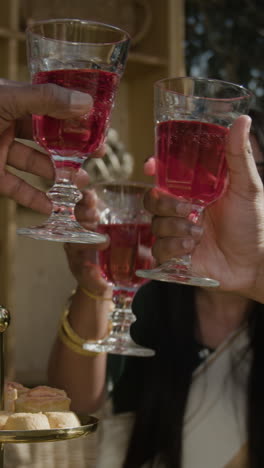 people toasting with red drinks at a social gathering with snacks