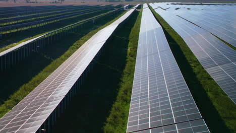 low flying over rows of large scale solar panel array farm