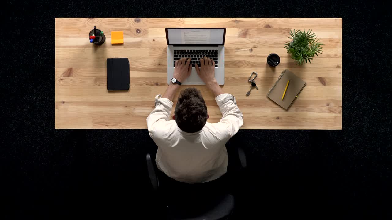 Giovane uomo arriva e lavora al laptop di giorno, concetto di lavoro, concetto di ufficio, concetto di comunicazione, ripresa dall'alto