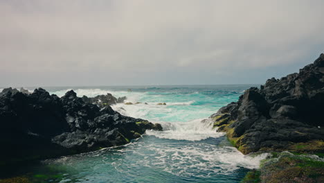 Slow-motion-shot-of-rough-ocean-waves-crushing-against-the-volcanic-rocky-coastline