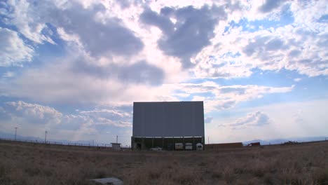 a screen under a big sky at an abandoned drive in theater