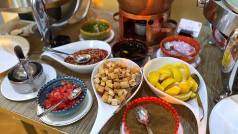 High-resolution footage of a vibrant condiment station featuring lemons, croutons, spices, chopped vegetables, and sauces—perfect for culinary, buffet, or hospitality visuals.