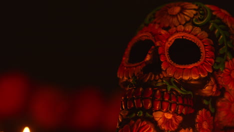 close up on still life of decorated skull lit by candles celebrating mexican holiday of dia de muertos or day of the dead 2