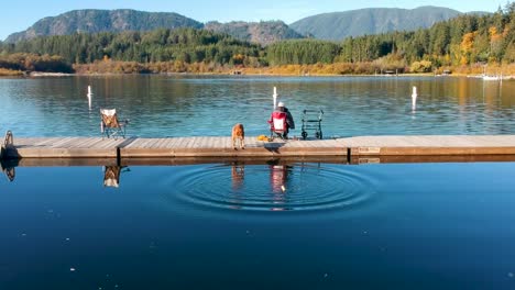 man throwing a stick for dog on dock in autumn