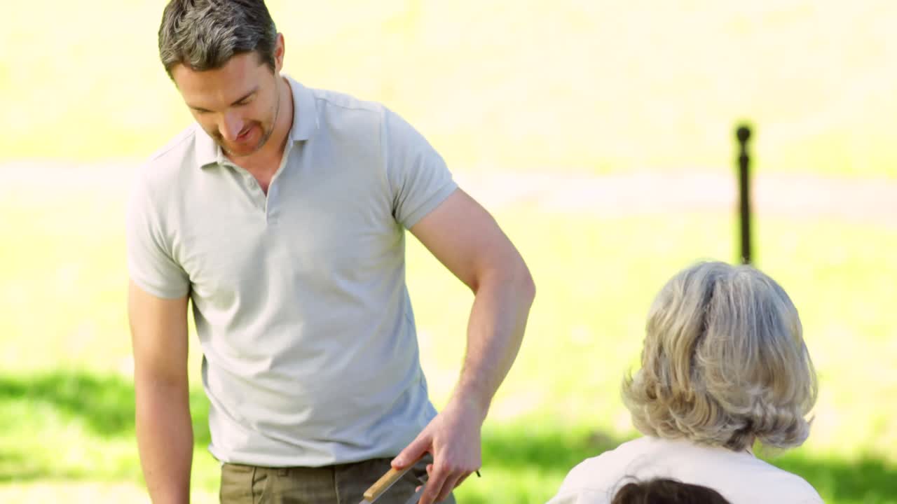 넓은 가족 이 공원 에서 바베큐 를 하고 있다