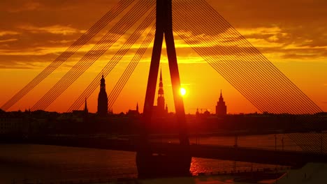 warm orange sunrise glows behind church towers as drone slowly drifts left