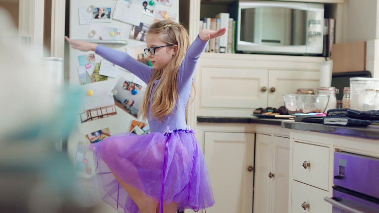 Bambina in tutù che balla in cucina