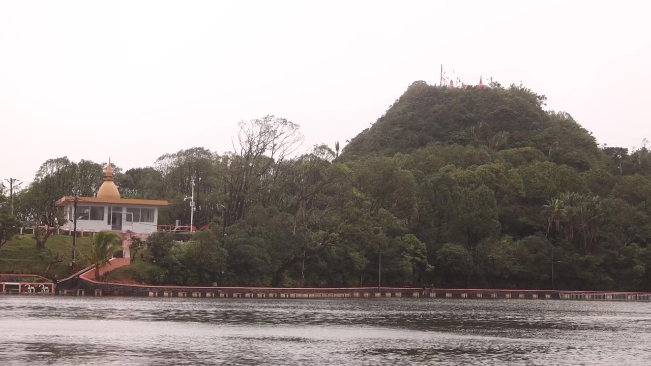 Vista del sacro complesso del tempio indù Ganga Talao accanto al lago vulcanico Grand Bassin a Mauritius. Sito di pellegrinaggio religioso circondato da colline boscose