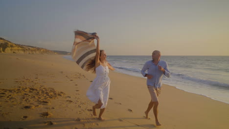 pareja feliz corriendo en la playa al atardecer