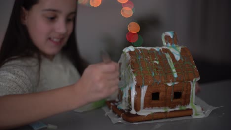 niña linda con pan de jengibre casa espeluznante con glaseado festivo y galleta en forma de fantasma. feliz halloween