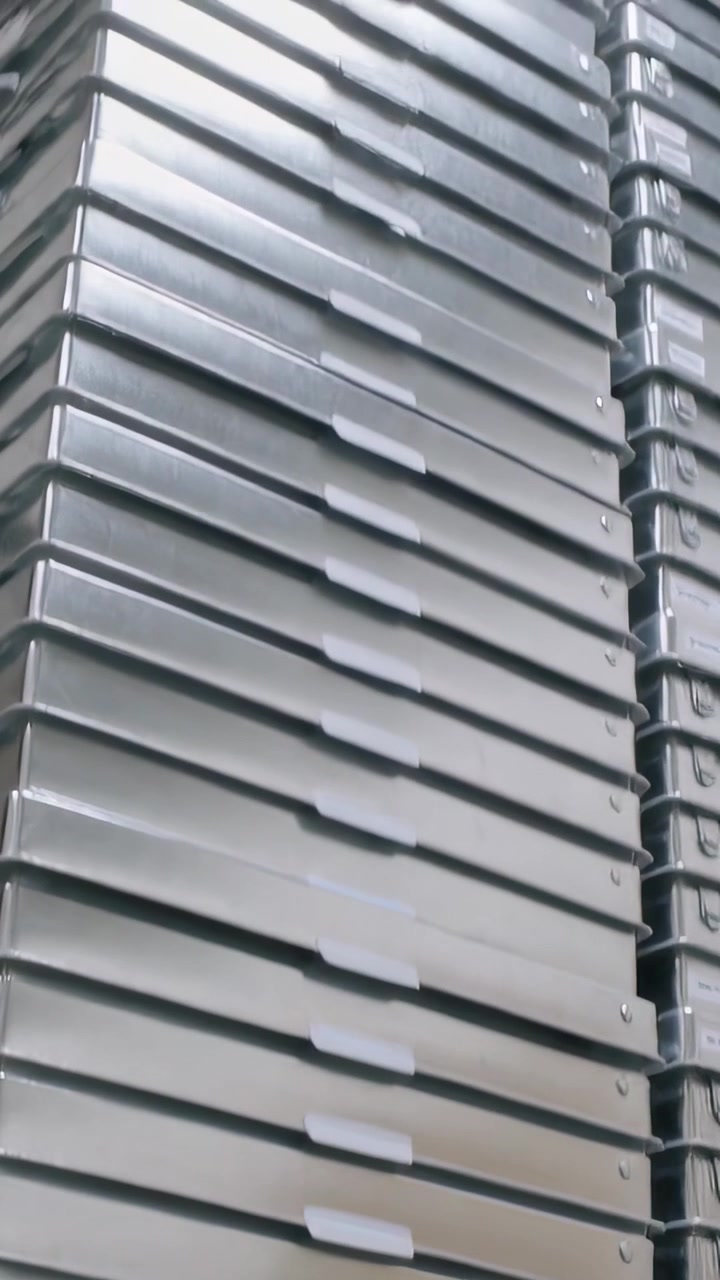 Video verticale: Telecamera che si inclina mostrando un'alta pila di vassoi vicino al soffitto in un magazzino con etichette bianche.