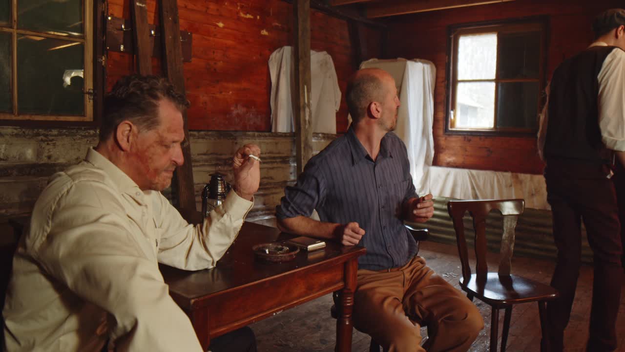 Two adults and a younger boy are smoking cigarettes in a 1930s setting. The boy coughs and gets sick from his cigarette