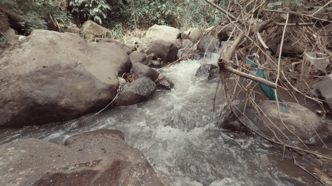 agua corriendo a través de rocas en un río sucio