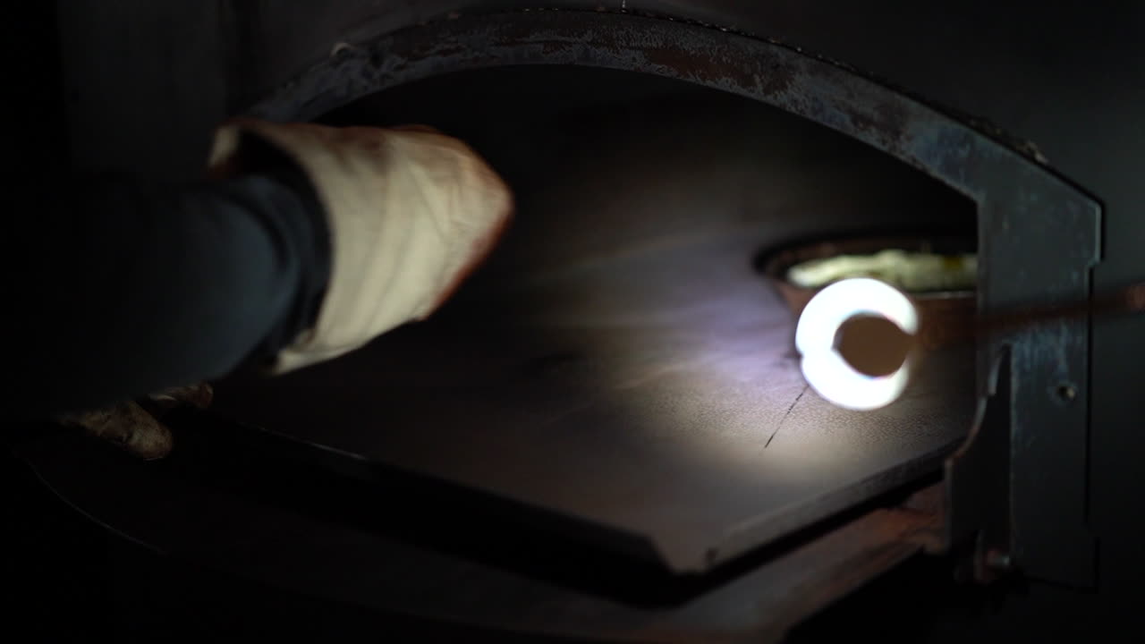 오래된 피자 오븐에 팬에 피자를 넣는 남자