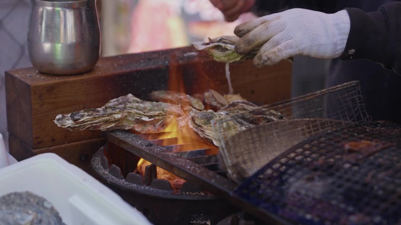 Fresh oysters cooking over charcoal fire at street food stall Tsukiji Outer Market Tokyo