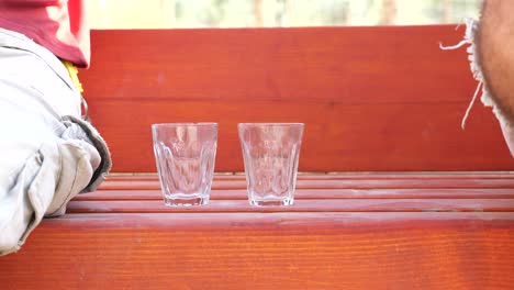 pouring-coffee-in-glass-cups-during-chit-chat-outdoors,-close-up-static-shot