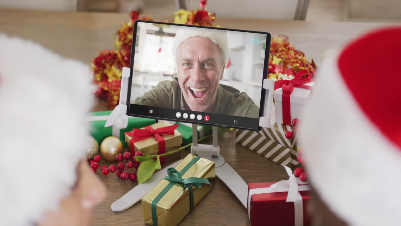 una pareja diversa tiene una llamada de video de navidad con un hombre caucásico mayor.