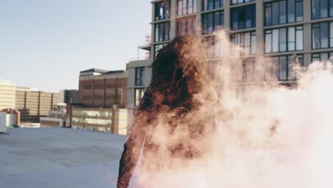 Fashionable-young-woman-on-urban-rooftop-using-a-smoke-grenade