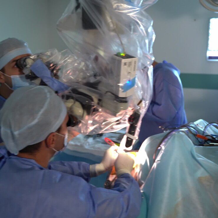 Usage of high technological equipment in neurosurgery. Doctors look into an advanced microscope to perform operation