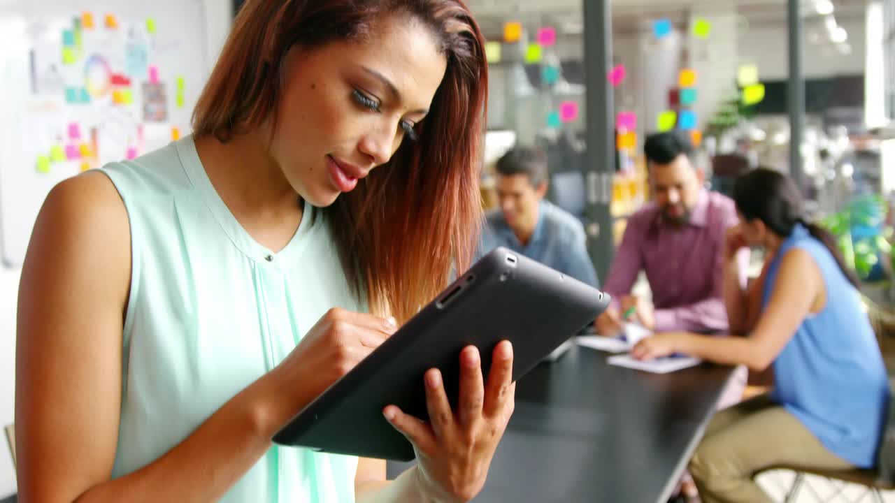 Woman tapping and swiping tablet in office making HUD UI on screen reviewing business with team