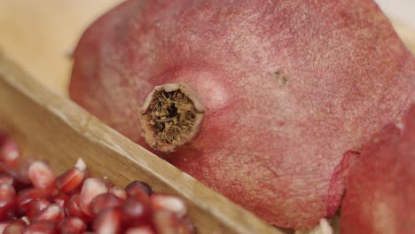 panning of pomegranate seeds to whole pomegranate in wooden plate juicing and using fresh ingredients and fresh whole pomegranates