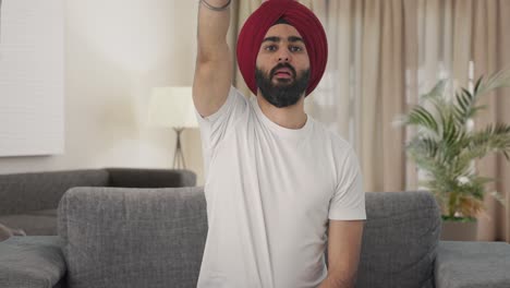 hombre indio sikh enojado tratando de arreglar el control remoto de la tv