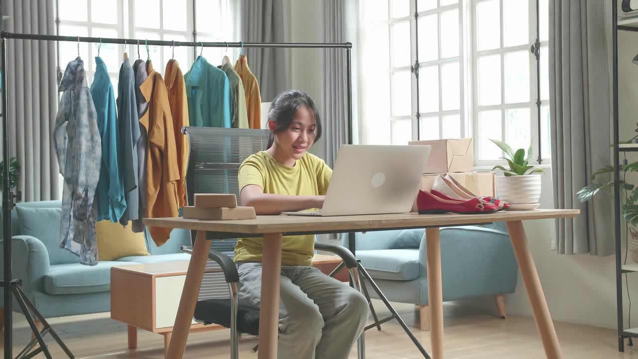 Gadis Muda Asia Penjual Online Mengetik di Komputer Sambil Menjual Pakaian di Rumah