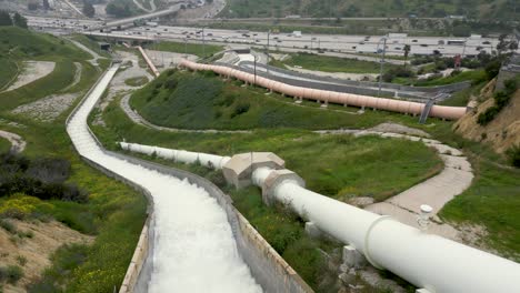 aerial drone of los angeles aqueduct releasing water and interstate 5 north south bound