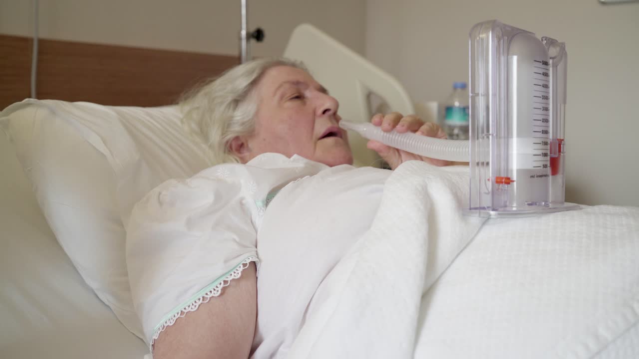 una anciana está haciendo un ejercicio de respiración inhalando una herramienta médica