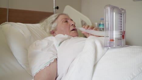 an old lady is doing a breathing exercise by inhaling a medical tool