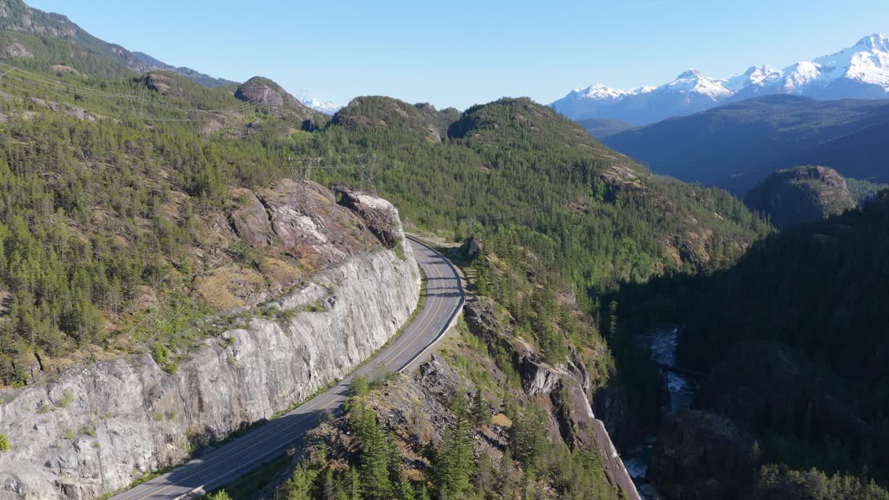 Scenic Mountain Highway Winding Through Lush British Columbia Forests Towards Snow-Capped Peaks, Canada