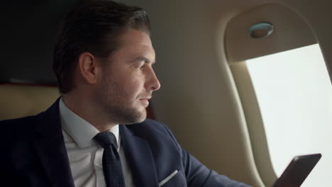 Company-owner-using-tablet-at-airplane-window-closeup.-Stressed-man-contemplate