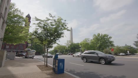 a side walk view of the washington monument that slowly pushes into a street with moving traffic in washington, dc