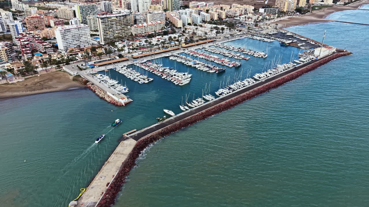 Barche ormeggiate nel marina con vista sulla città costiera e acqua limpida di giorno in una vivace località marittima