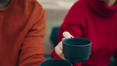 hands holding thermos cup on nature close up. man pouring beverage on picnic.