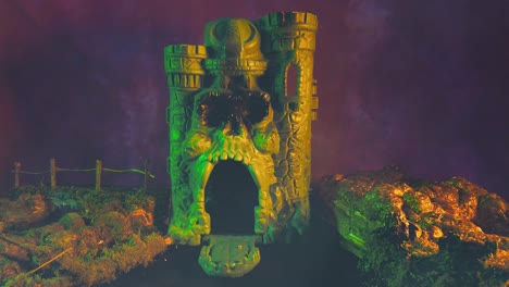 set design with miniature gray skull castle against foggy night sky with surreal lighting