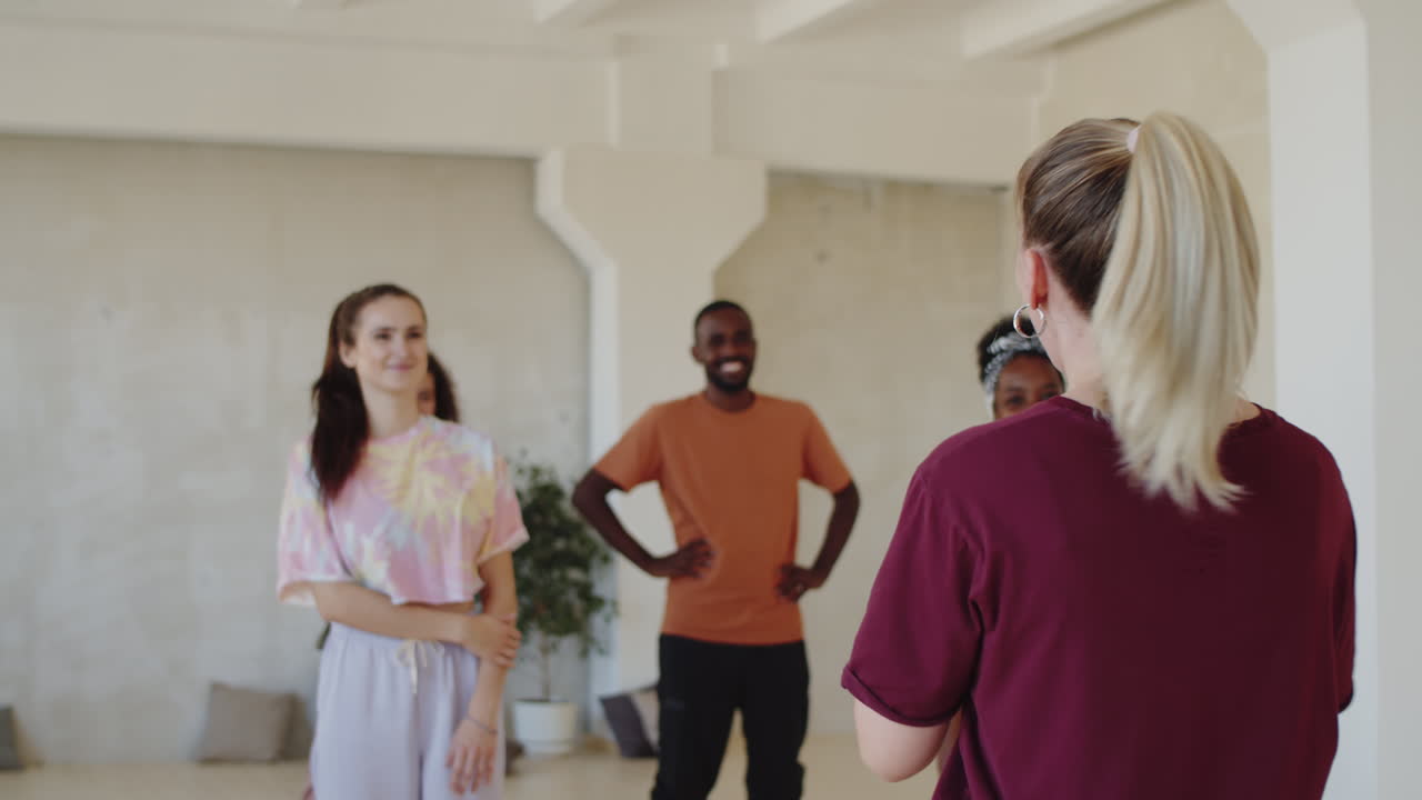maestra de danza hablando con estudiantes multiétnicos en el estudio