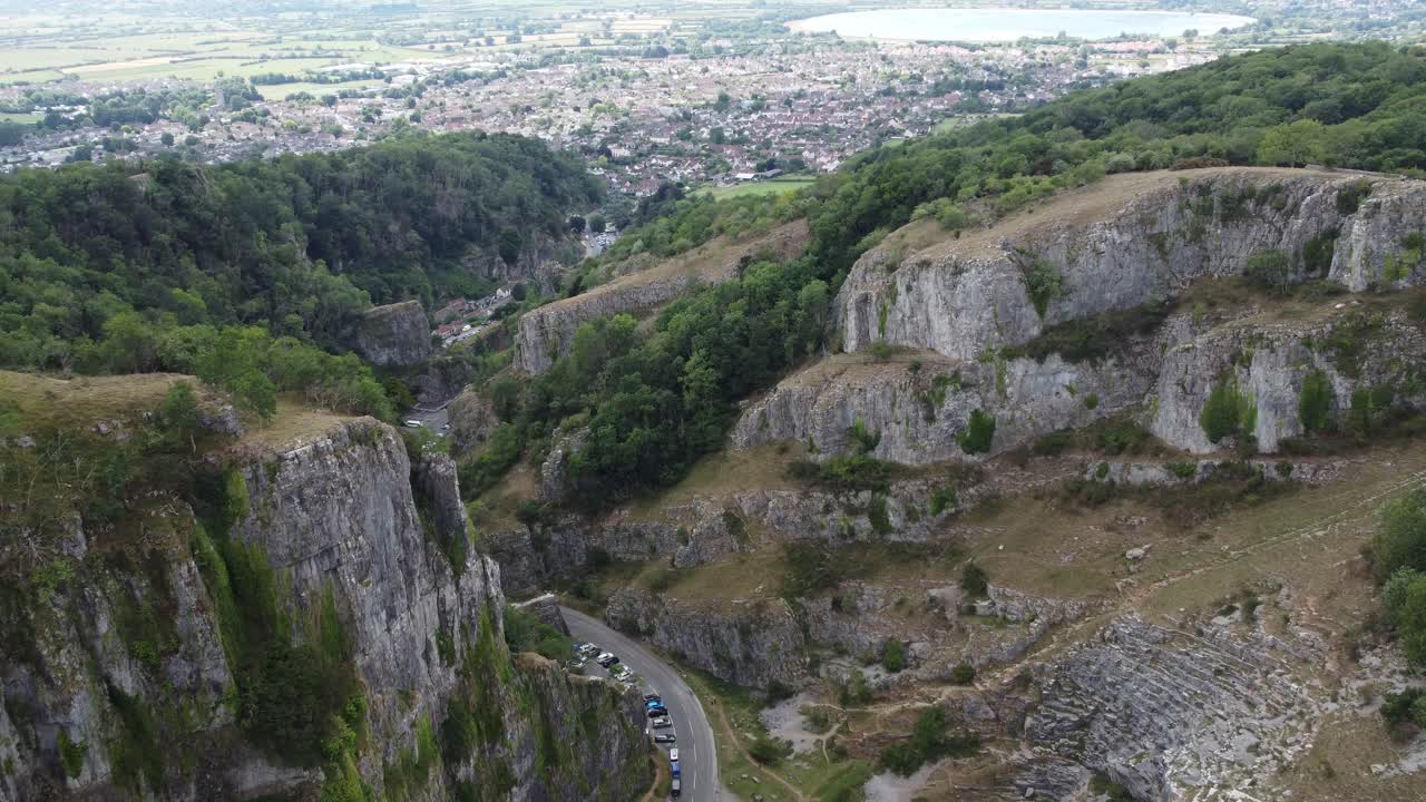 Aerial vista of the limestone cliff formations at Cheddar gorge in the Mendip Hills, Somerset, with the village of Cheddar in the background