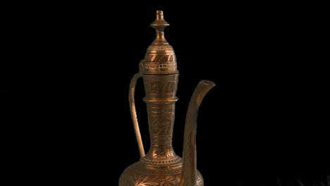 Carved-brass-Arabic-Ewer-pot-rotates-isolated-on-black-background