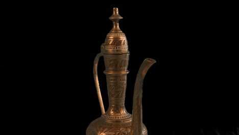 carved brass arabic ewer pot rotates isolated on black background